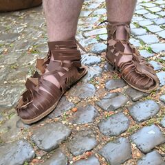 feet in roman sandals on cobblestone